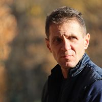 一位中年男性编辑坐在书桌前核对打印出的公文样张与屏幕上OFD原件，桌上有放大镜与红笔，暖色台灯照明